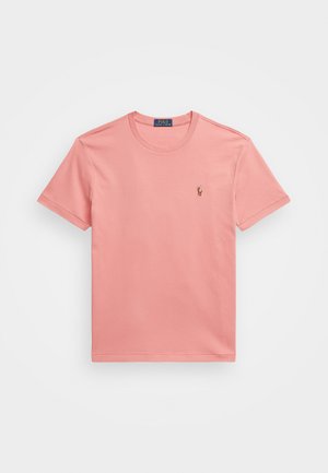 Rosa bomullströja med rund halsringning och korta ärmar. Har en liten broderad logotyp på vänster bröst. Enkel, slät textur.