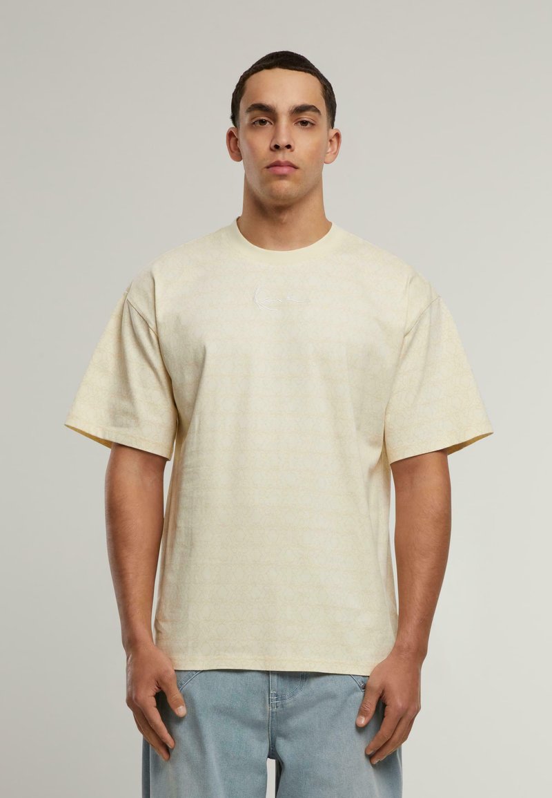 Šviesiai geltonos trumpomis rankovėmis marškinėliai, dekoruoti subtiliu raštu ir mažuoju šviesiu logotipu ant krūtinės. Laisvas kirpimas ir medvilnės medžiaga.