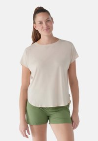 Lys beige kortærmet t-shirt med rund halsudskæring og løstsiddende pasform, parret med grønne shorts med forlommer og stikninger.