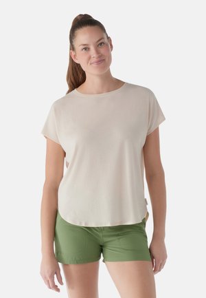 Helles beige T-Shirt mit kurzen Ärmeln, rundem Halsausschnitt und lockerer Passform, kombiniert mit grünen Shorts mit Fronttaschen und Nähdetails.