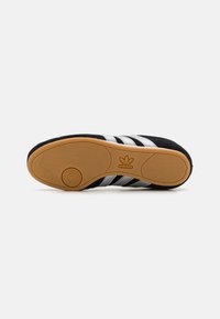Black suede sneaker with three silver stripes, rubber sole, and textured gum bottom. Includes Adidas logo on the heel.