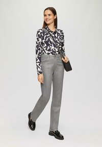 Chemise à manches longues en bleu marine avec un motif abstrait blanc ; pantalon gris taille haute ; chaussures noires ; sac bandoulière avec une apparence texturée.