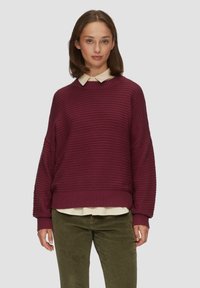 Pull en ribbed bordeaux avec épaules tombantes et un large col, superposé sur une chemise légère à col. Tissu texturé, coupe décontractée.