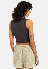 Mörkgrå, kort tanktopp med ribbad textur, tillsammans med ljusgröna shorts med bladmönster och elastisk midja.