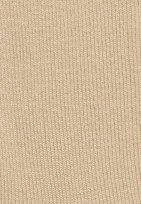 Beżowy materiał o prążkowanej fakturze, ukazujący pionowe linie i gładką powierzchnię. Brak wyraźnych wzorów lub ozdób.