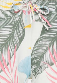 Pantalones cortos blancos con un patrón de hojas tropicales en verde, rosa y azul. Incluyen un cordón trenzado con acentos multicolores.