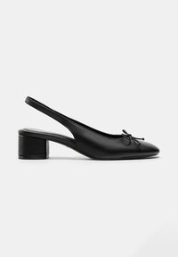 Chaussure slingback en cuir noir avec petit talon bloc, bout pointu et petit nœud décoratif à l'avant.