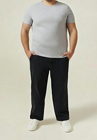 Šedé tričko s krátkým rukávem v kombinaci s černými kalhotami, které mají boční kapsy, a bílými botami. Materiál vypadá hladký a pohodlný.