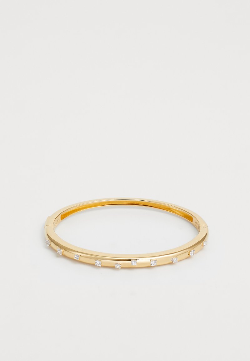 Guldtonad bangle-armband med en slät yta och ett geometriskt mönster, prytt med små klara kristaller jämnt fördelade längs banden.