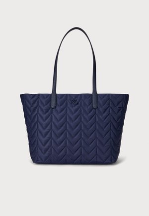 Bolso tote acolchado azul marino con patrón de chevron, equipado con dos resistentes asas de cuero y un logo grabado en relieve en la parte frontal. Base plana para mayor estabilidad.