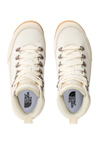 Kremfargede kanvas sneakers med metalliske snørehull og hvite snøringer. Har en gummisåle og "The North Face"-logo på tunga og sålen.