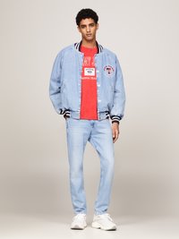 Denim bomberjakke med marineblå og hvite striper på kragen, lyseblå farge, grafisk rød T-skjorte under, lyseblå jeans og hvite joggesko.
