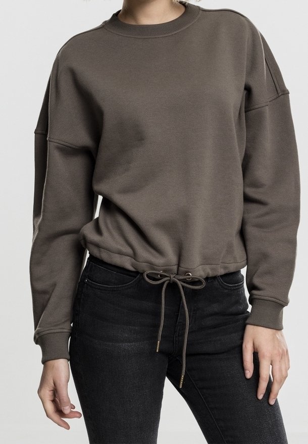 Sudadera marrón de tejido suave, con mangas largas, cuello redondo y un dobladillo con cordón. Combinada con jeans oscuros.