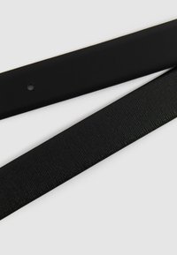 Cinturón de cuero negro con un acabado suave, que presenta una franja texturizada. El cinturón es plano y estrecho, con un agujero redondeado para ajustes.