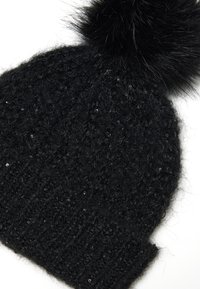 Zwarte gebreide beanie met een gestructureerd patroon en een grote zwarte nepbont pompon bovenop. Heeft een geribde manchette aan de basis.