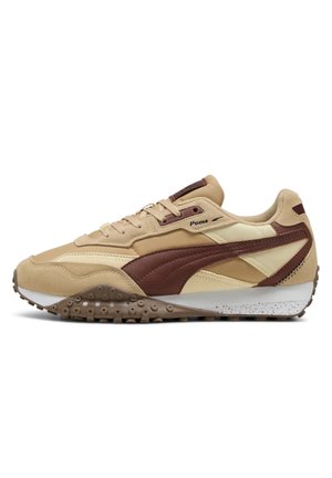 Scarpa da ginnastica Puma beige e marrone con suola strutturata, chiusura con lacci e logo sul lato, mostrata su sfondo bianco.