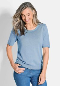Hellblaues Kurzarm-Sweatshirt aus Rippstoff mit rundem Halsausschnitt und lockerer Passform, kombiniert mit blauen Jeans.