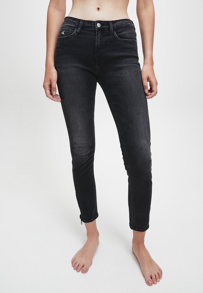 Jeans skinny de mezclilla negra con cintura alta, que cuentan con detalles de cierre en los tobillos y un desvanecimiento sutil. Diseño clásico de cinco bolsillos con detalles en plata.