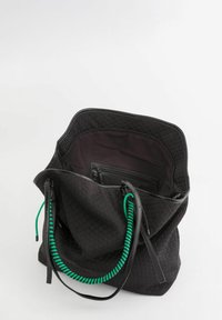 Czarna torba na ramię o heksagonalnej teksturze zewnętrznej, z zielonymi i czarnymi paskami oraz pojemną wewnętrzną kieszenią z zapięciem na zamek.