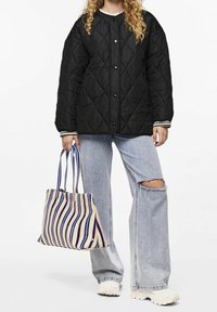 Black quilted jacket with a round neck and snap buttons. Light blue denim jeans with a tear. Striped beige and navy tote bag with dual handles.