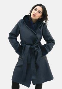 Navy faux leather coat with a wrap design and a wide, soft collar. Features a tie belt and textured sleeves for added detail.