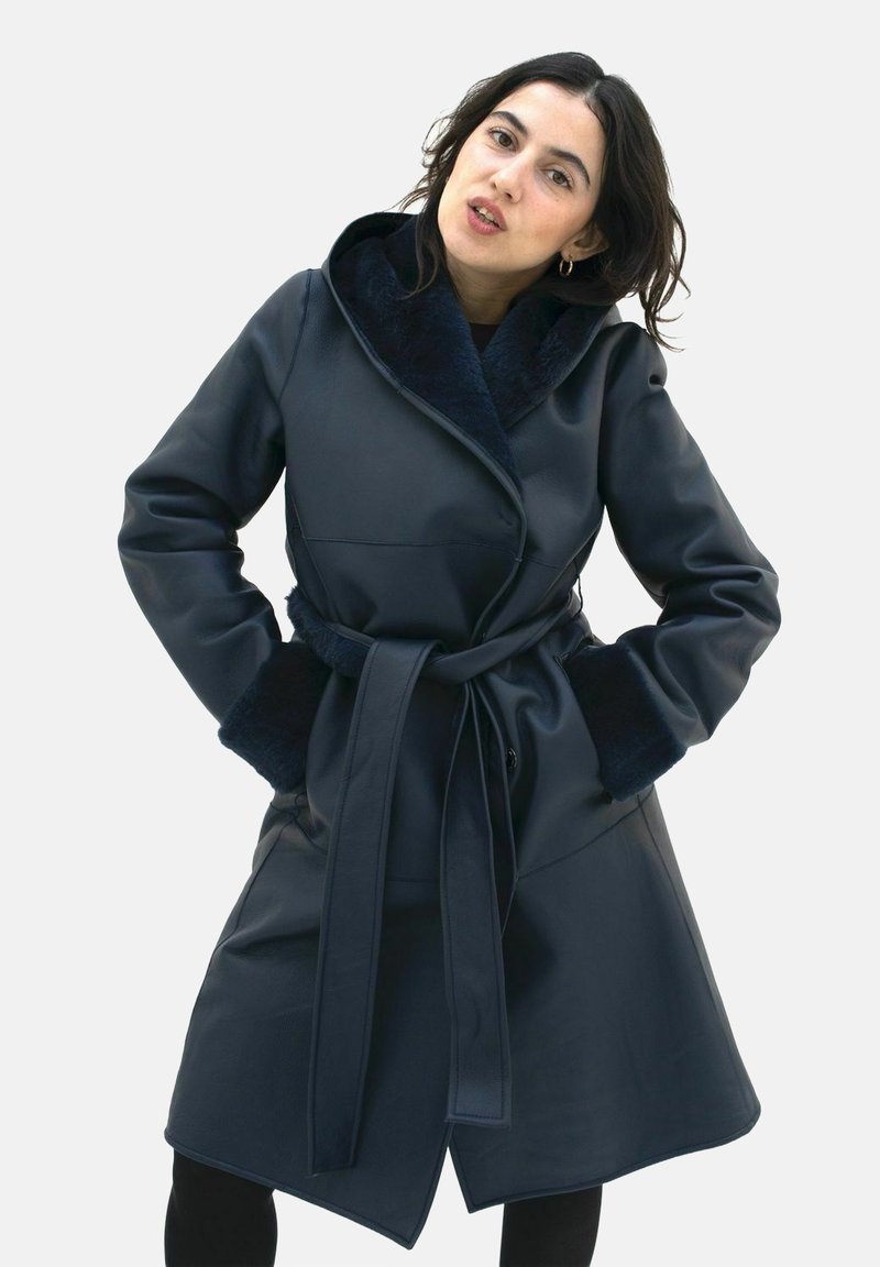 Navy faux leather coat with a wrap design and a wide, soft collar. Features a tie belt and textured sleeves for added detail.