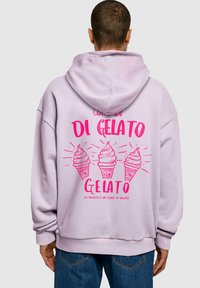 Lila kapucnis pulóver, amelynek hátán három rózsaszín fagylalt-kúp látható, valamint a "CONO DI GELATO" és a "GELATO" felirat.