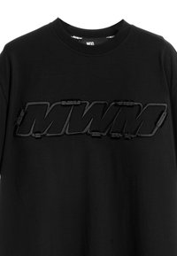 Camiseta de algodón negra con un logotipo "MWM" texturizado y bordado que se muestra de manera prominente en el pecho. Cuello redondo clásico.