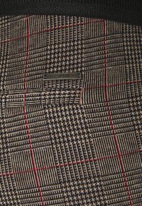 Tessuto a quadri con una miscela di marroni, neri e rossi. Include un'etichetta metallica "ESPRIT". Texture con vari modelli e trame.