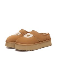 Brown slip-on shoes with a soft, textured surface and plush white lining, featuring a thick, ridged rubber sole for comfort.