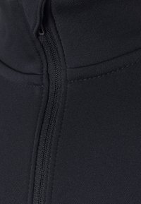 Musta urheilullinen paita, jossa korkea kaulus, sileä pinta ja keskellä vetoketju, jossa kontrastivärinen ommel, ihanteellinen aktiiviseen käyttöön.