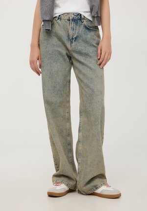 Jeans a gamba larga in denim azzurro chiaro con sbiaditure, design a cinque tasche, chiusura con bottone e texture leggermente strappata.