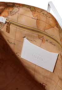 Interno di una borsa bianca con una stampa della mappa del mondo in toni caldi, dettaglio della cerniera dorata e un'etichetta in pelle bianca con la scritta "CLASSE" impressa.