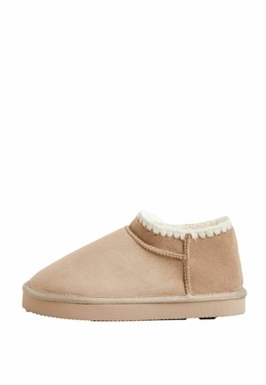 Beige slipper made of soft suede with a fleece lining and a textured rubber sole. Features a stitched trim along the top edge.