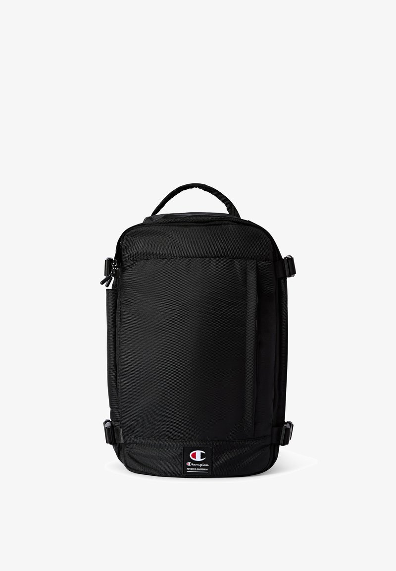 Sac à dos noir en tissu résistant avec une poche zippée à l'avant, des sangles ajustables et une poignée. Comprend un patch logo en bas.