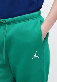 Zelene trenirke iz mešanice bombaža. Imajo elastičen pas z vrvico, stransko žep in bel Jumpman logotip.