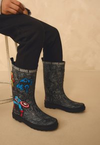 Svarta gummistövel med Marvel-serietidningsmotiv. Har färgglada superhjältegrafik, lågprofilsula och bekväm passform.