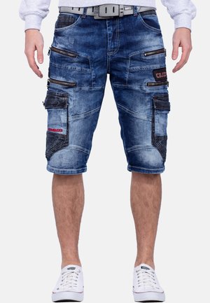 Pantaloni cargo in denim di colore blu invecchiato con multiple tasche con zip e una vestibilità comoda. Presentano cuciture in contrasto e una cintura.