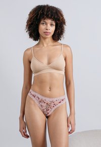Μπεζ μπραλέτ με λεπτές τιράντες και ροζ εσώρουχα από λουλούδια. Διαθέτει απαλό υφή με λεπτές δαντελένιες λεπτομέρειες και λουλουδάτο μοτίβο.