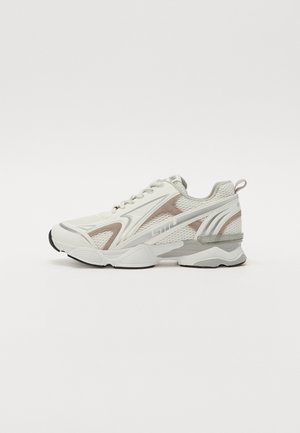 White athletic sneaker with mesh panels, smooth accents, and cushioned sole. Features laces, logo, and a textured back for support.
