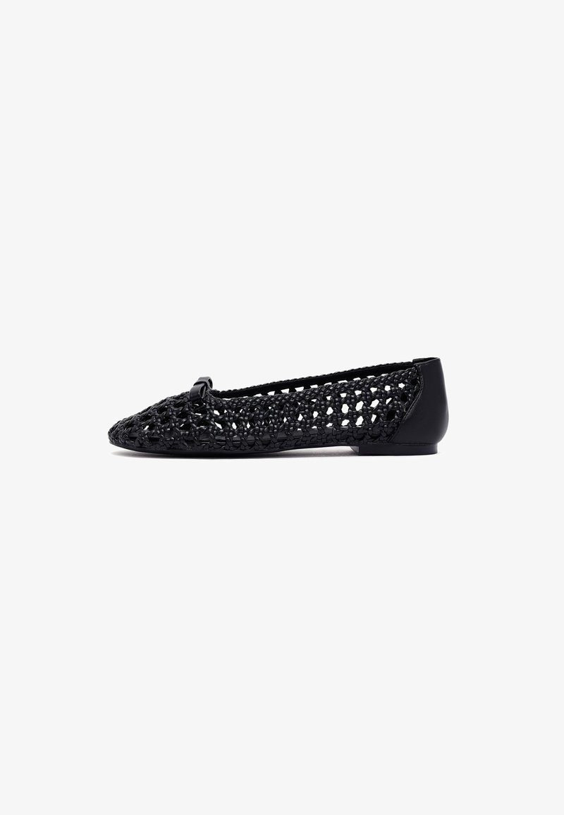 Botte noire à semelle plate avec un design supérieur tissé et un motif texturé, bout arrondi et un petit nœud en accent sur le devant.