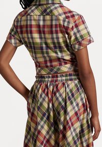 Short-sleeve plaid shirt and matching skirt. Features red, green, yellow, and blue check patterns. Elastic waistband on the skirt.