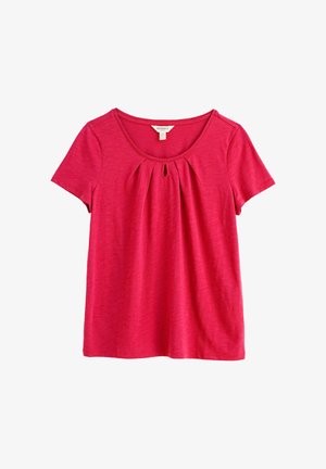 Svetlo roza majica s kratkimi rokavi, okrogel izrez, majhen ključavnica in sprednje naborke, položena ravno na belem ozadju.