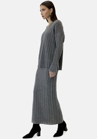 Gray ribbed knit sweater and maxi skirt set, featuring long sleeves and a V-neck, with black ankle boots and a smooth texture.