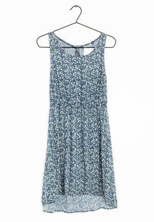 Blaues ärmelloses Kleid mit weißem Blumenmuster, an einem schwarzen Drahtbügel vor weißem Hintergrund hängend.
