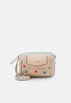 Bolso bandolera beige con diseños de sol y flores bordados en colores, bolsillo frontal con solapa y correa ajustable sobre fondo liso.