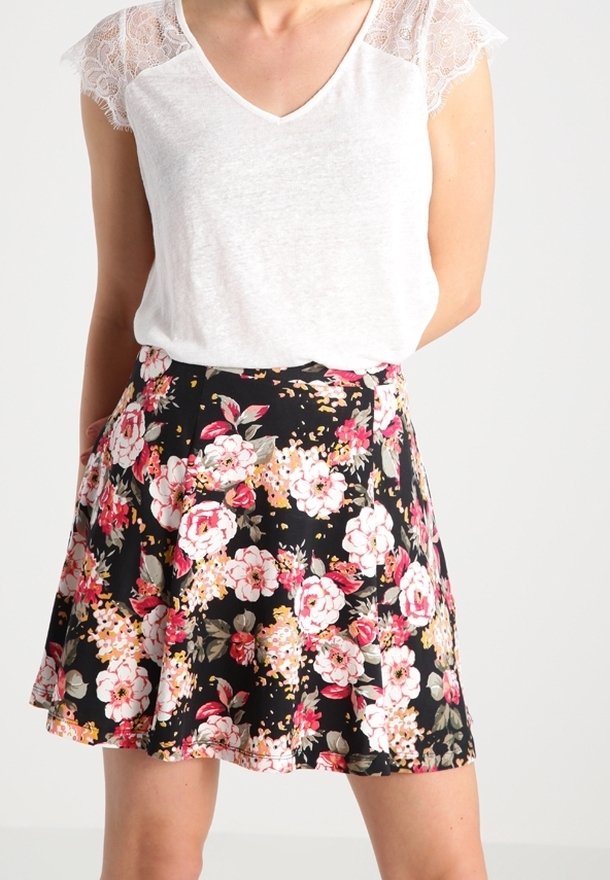 Bílé tričko s výstřihem do V a krajkovými krátkými rukávy, doplněné černou květinovou sukní s růžovými a krémovými květy, rozšířeným střihem a bočními kapsami.