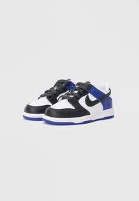 Crne, bijele i plave Nike tenisice s kožnim gornjištem, teksturiranim premazima i podstavljenim ovratnikom. Imaju klasični dizajn s vezanjem i gumeni potplat.