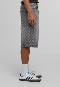 Grau denim Cargo-Shorts mit einem strukturierten Kreis-Muster, Seitentaschen und geradem Schnitt, kombiniert mit weißen Socken und schwarzen Sneakers.