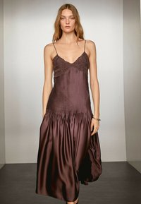 Langes braunes Satin-Kleid mit Spitzenakzenten und dünnen Trägern. Es hat ein plissiertes Oberteil und einen ausgestellten Rock mit gerafften Details am Saum.